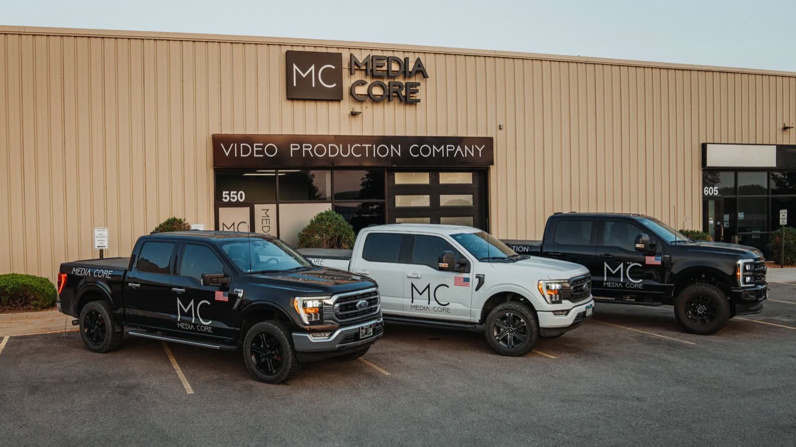 Three Media Core work trucks parked outside the Media Core video production building